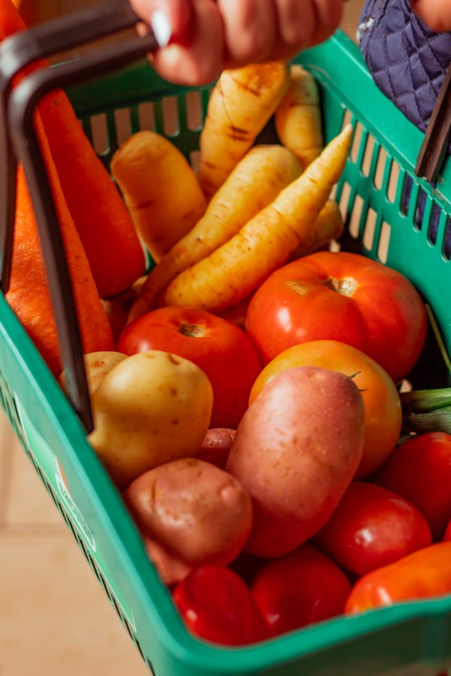 Cliente segurando sua cesta de compras, com alimentos saudáveis e de qualidade.