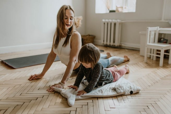 Mãe e filha, fazendo alongamento em casa.
