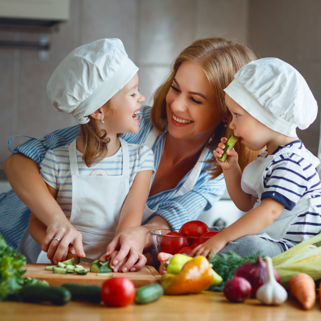Mãe ensinando seus filhos a cozinharem uma refeição saudável.
