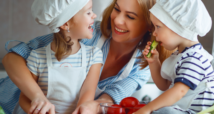 Mãe ensinando seus filhos a cozinharem uma refeição saudável.