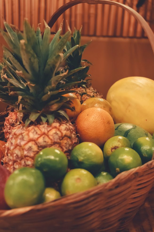 Frutas cítricas na cesta, sendo elas: abacaxi, limão e laranja.