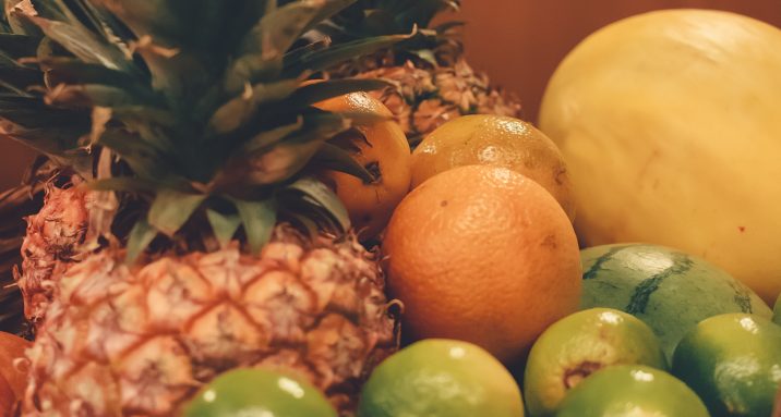 Frutas cítricas na cesta, sendo elas: abacaxi, limão e laranja.