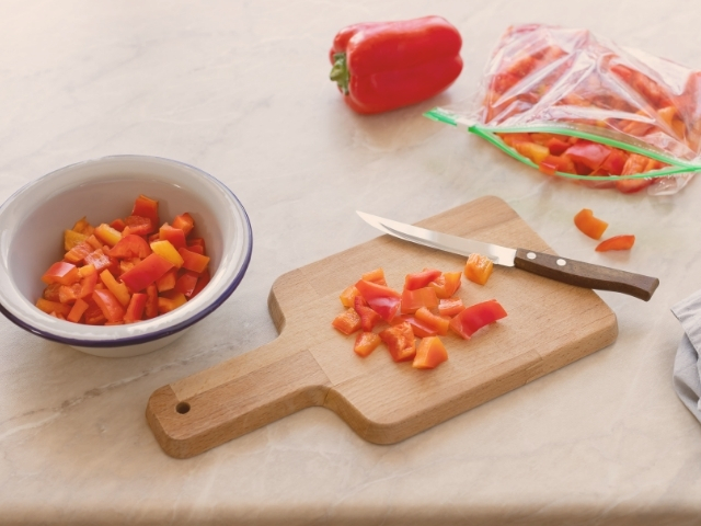 Tomates picados em uma tábua de madeira, e alguns estão reservados em um pote, para o preparo de receitas.